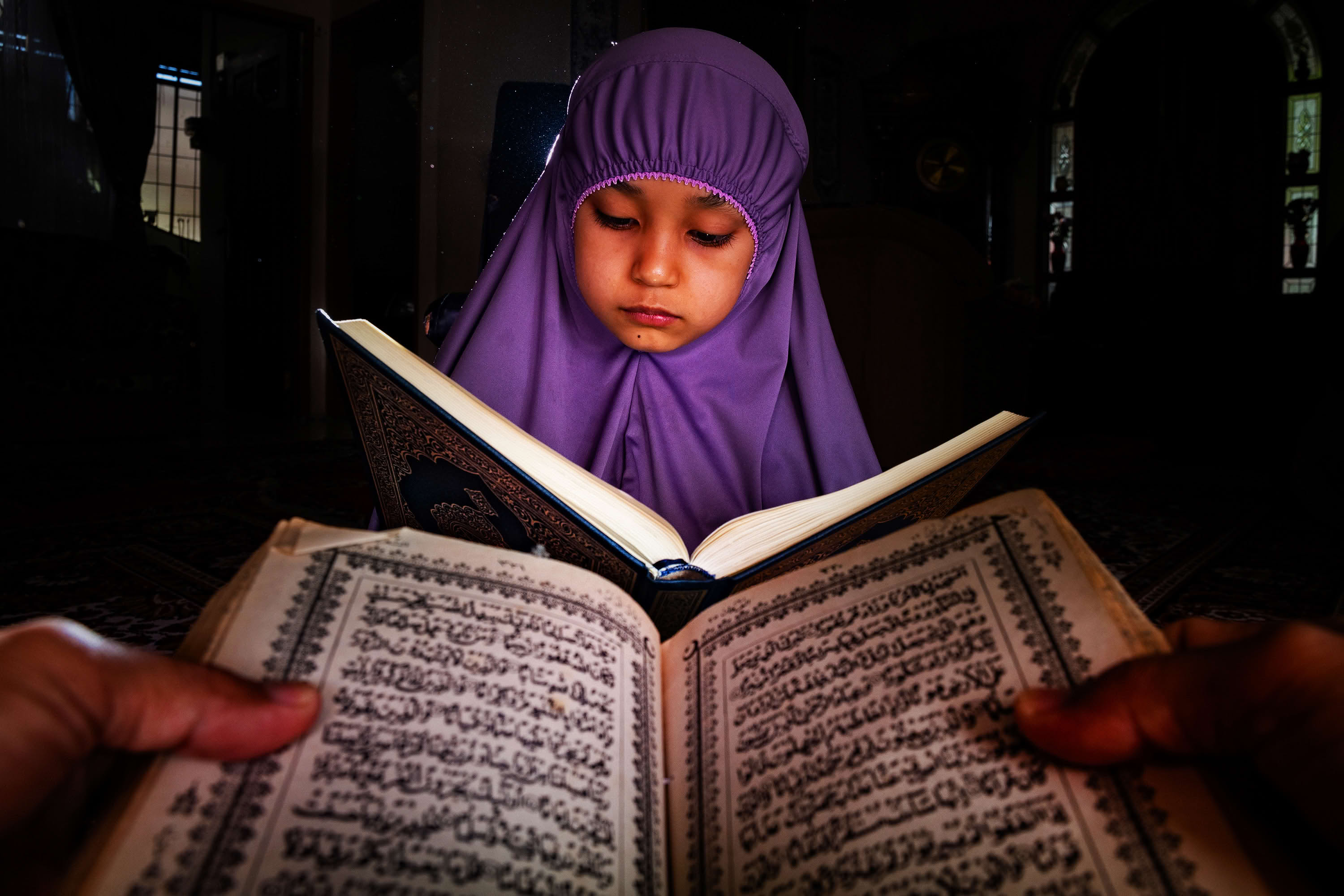 Anak belajar membaca Al Quran bersama gurunya